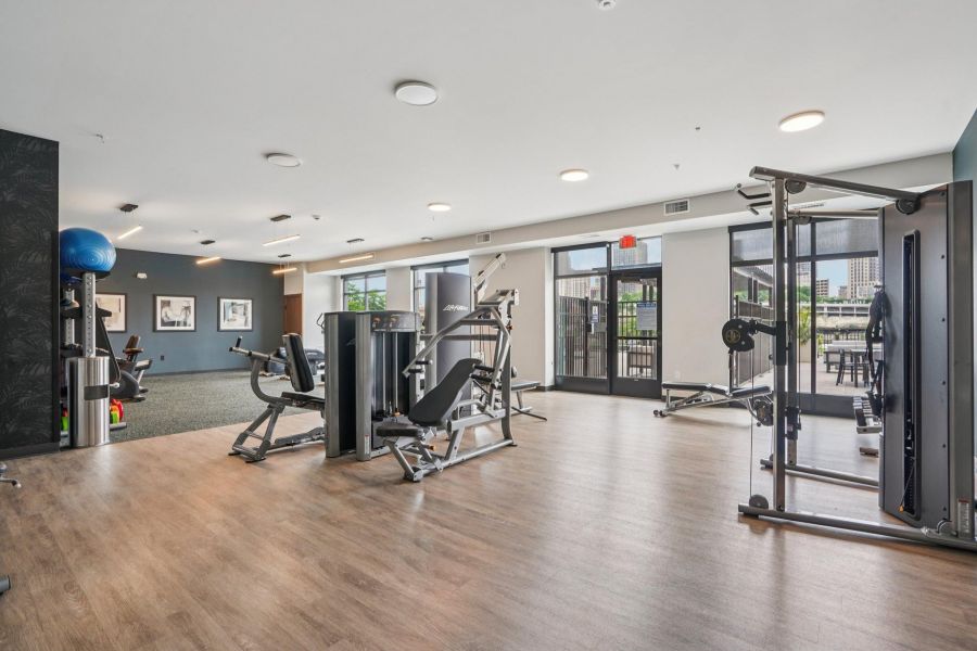 The Scenic modern gym with exercise machines, weight equipment, wooden floors, and large windows letting in natural light.