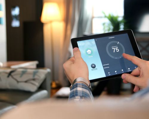 man using tablet to control thermostat with smart home technology