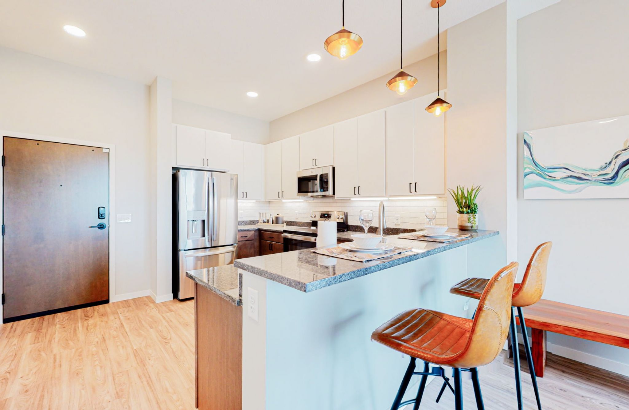 The Scenic penthouse apartment kitchen with designer finishes, a large kitchen peninsula, stainless steel appliances, and pendant lighting