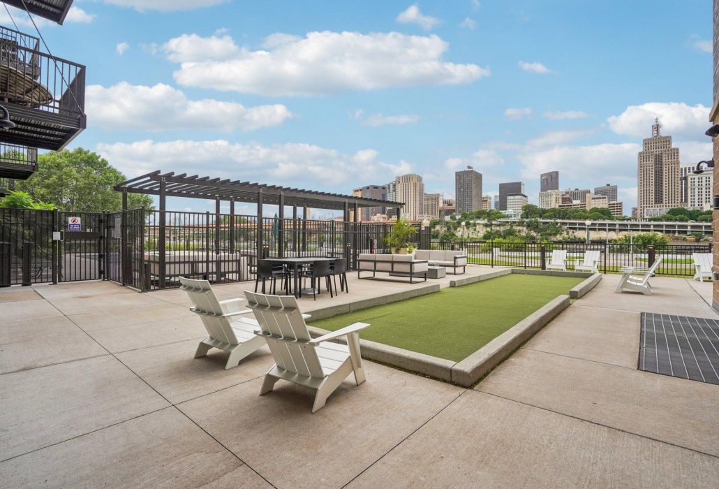 The Scenic rooftop patio with a bocce ball court, seating, pergola, and city skyline in the background.