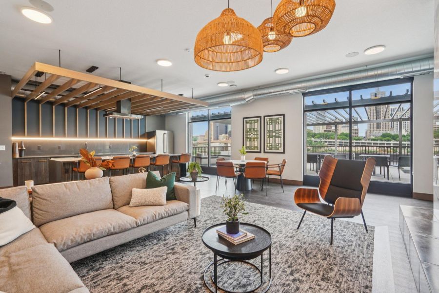 The Scenic modern open-plan living room with a sofa, armchair, dining area, and kitchen, featuring large windows.