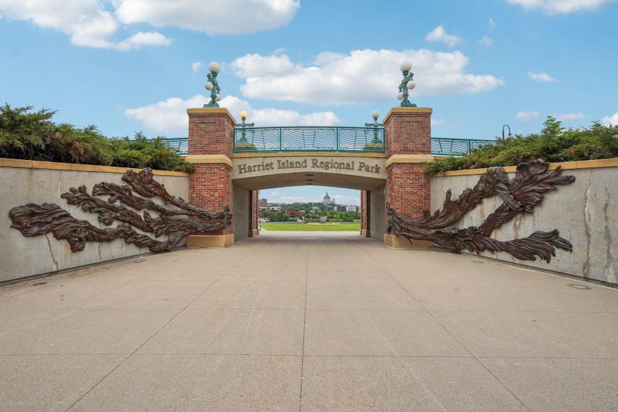The Scenic brick archway entrance to Martin Road Regional Park with a paved path, greenery, and blue sky above.